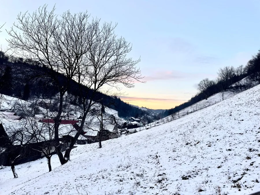 Snow-covered valley at dusk, between the hills